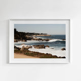 Framed photograph of a coastal scene with waves and rocky shoreline.